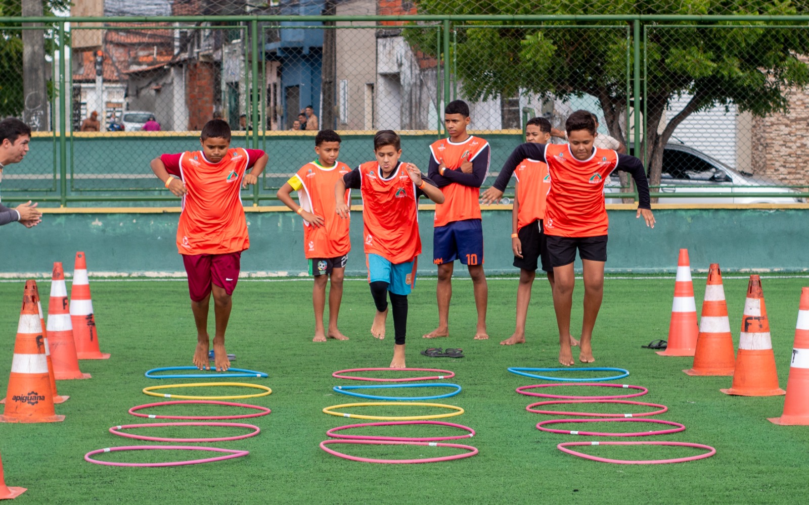 adolescentes correndo no gramado de uma Areninha
